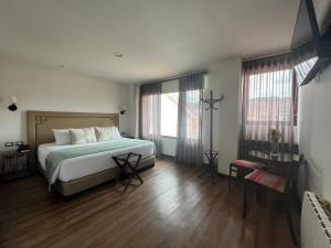 1 dormitorio con 1 cama, suelo de madera y ventanas en Casa Esmeralda by Katari, en Cusco