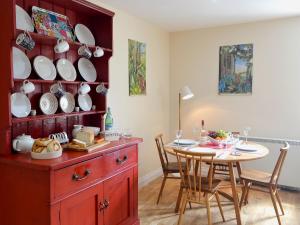 a dining room with a table and a red cabinet at Brierdene End Cottage in Hartley