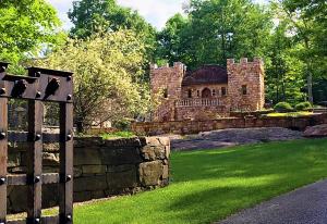 a stone building with a fence in front of a yard at HIGHLANDS CASTLE overlooking Lake George plus 2 other CASTLES & SUITES in Bolton Landing