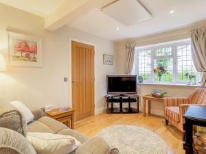 uma sala de estar com um sofá e uma televisão em Garden Cottage em Burgh