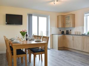 a kitchen and dining room with a wooden table and chairs at Benwells Holiday Cottage in Maud