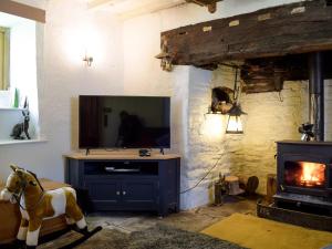 a living room with a television and a horse statue at Lower Goytre Farmhouse in Llanvair Waterdine