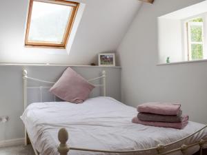 a bedroom with a bed with pink pillows and a window at Lower Goytre Farmhouse in Llanvair Waterdine