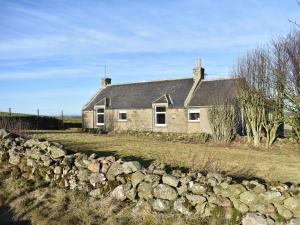 a stone house with a stone wall in front of it at Benwells Holiday Cottage in Maud