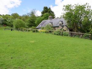 een oud huis met een hek en een grasveld bij Lower Goytre Farmhouse in Llanvair Waterdine