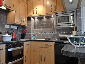 a kitchen with wooden cabinets and a microwave at Rainbows End in Bowness-on-Windermere