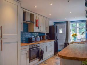 a kitchen with white cabinets and a wooden counter top at The Old Post Office in Aston Cantlow