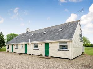 un edificio blanco con puertas verdes y techo en Jubileum Lodge uk27999, en Watton