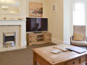 a living room with a fireplace and a table at Filey House in Sheringham