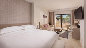 Fuente AlamoにあるOna Hacienda del Álamo Golf Resortのベッドルーム(白いベッド1台付)、リビングルームが備わります。