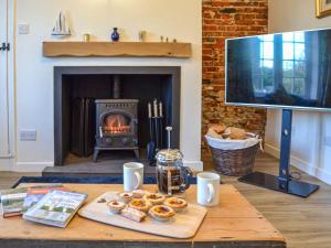 una mesa con donuts y una chimenea en la sala de estar. en Rosemary Cottage en Stalham