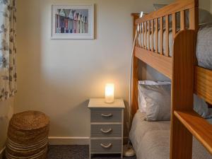 Dormitorio con litera y mesita de noche con velas en Rosemary Cottage en Stalham