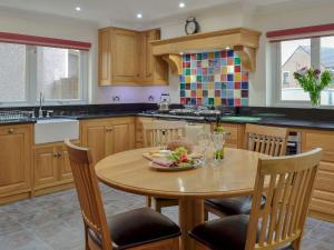 una cocina con una mesa con un bol de fruta. en Hawthorn Cottage en Stranraer