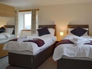 a bedroom with two beds and a window at Hawthorn Cottage in Stranraer