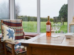 a bottle of wine sitting on a table with glasses at Forda Farm in Black Torrington