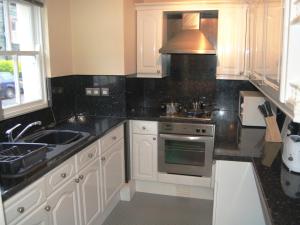 cocina con armarios blancos, fregadero y fogones en Helvellyn House Apartment, en Keswick
