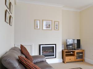 sala de estar con sofá de cuero y TV en Helvellyn House Apartment, en Keswick
