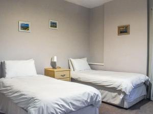2 camas en una habitación de hotel con sábanas blancas en Baileys Retreat, en Sneaton