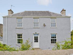 a gray house with a white door at Ford Farmhouse in Carew