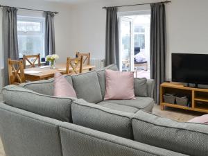 a living room with a gray couch with pink pillows at Spring Tides in Beadnell