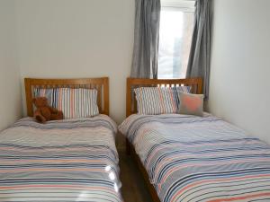 two beds in a room with a teddy bear sitting on them at Spring Tides in Beadnell
