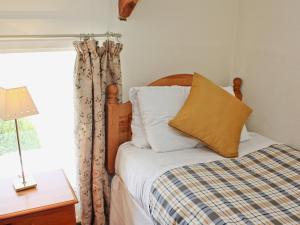 a bedroom with a bed with a pillow and a window at The Granary Cottage in Warenford
