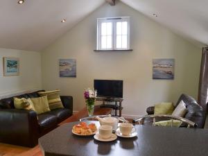 a living room with a table and chairs and a television at Aprils Cottage in Kilkhampton