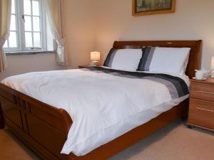 a bedroom with a large bed with a wooden frame at Aprils Cottage in Kilkhampton