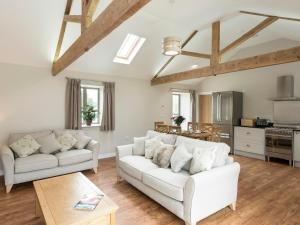 sala de estar con 2 sofás blancos y cocina en Property 2 en Wroxall