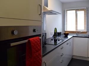 - une cuisine avec des placards blancs et une serviette rouge dans l'établissement Crossburn Hideaway, à Helensburgh