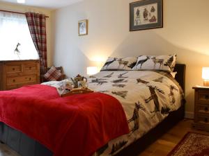a bedroom with a bed with a red blanket on it at Crossburn Hideaway in Helensburgh