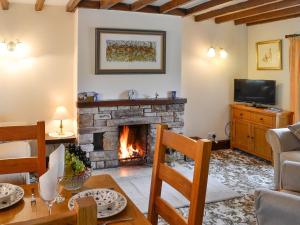 a living room with a fireplace and a table and chairs at Swaledale Cottag in Caldbeck