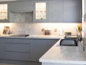 una cocina con armarios grises y fregadero en 4 Mote View-uk37497, en Sandhead