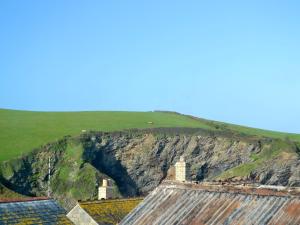 a cave in the side of a mountain with houses at Saundrys Barn in Port Isaac
