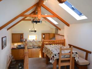 a kitchen with a dining room table and a kitchen with wooden cabinets at Saundrys Barn in Port Isaac