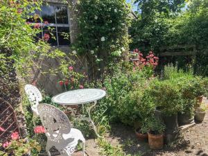 una mesa y sillas en un jardín con plantas en Garden Flat, en Pilton