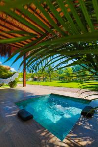 a swimming pool under a large wooden roof at Bahay Tatu in Pôrto de Pedras