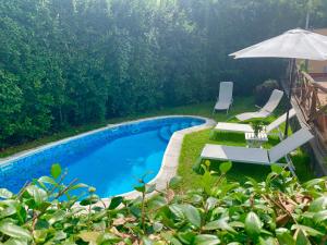 een zwembad met 2 stoelen en een parasol bij Casa Gino Petrulli Etna, villa con piscina in Zafferana Etnea