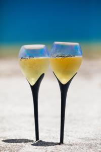 two glasses of wine sitting on the beach at Bahay Tatu in Pôrto de Pedras