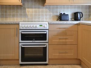 una cocina con horno blanco y armarios de madera en Stable Cottage 8 - Ukc3747 en Bawdeswell