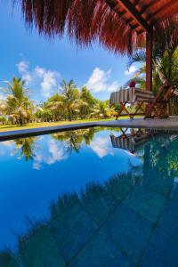 a swimming pool with a chair and palm trees at Bahay Tatu in Pôrto de Pedras