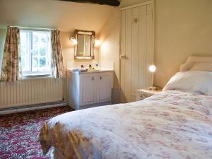 a bedroom with a bed and a mirror and a window at Cerne Abbey Cottage in Cerne Abbas