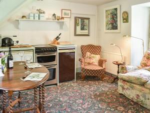 a living room with a table and a kitchen at Cerne Abbey Cottage in Cerne Abbas