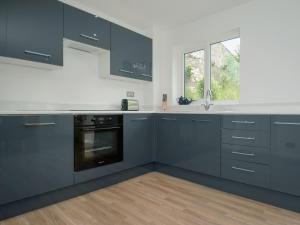 a kitchen with gray cabinets and a window at Little Orchard in Farmborough