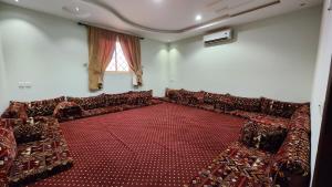 an empty room with red chairs and a window at مزرعة الطيبين in Buraydah