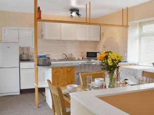 una cucina con armadi bianchi e un tavolo con fiori di The White Cottage a Furness Vale