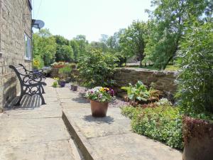 a garden with a bench and flowers and a stone wall at The White Cottage in Furness Vale