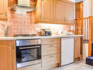 a kitchen with wooden cabinets and a stove top oven at Over Across-uk38277 in Cloughton