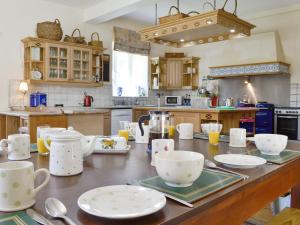 een keuken met een tafel met kopjes en borden erop bij Crogen Coach House - Oqr in Llandrillo