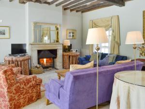 a living room with a purple couch and a fireplace at Crogen Coach House - Oqr in Llandrillo